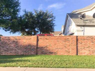 Kırmızı tuğla alt bölümü duvarlar Irving, Texas, bariyer mahalle konut evler ve yol ile genel yol hakkı işlek cadde arasında uydu tv. Ekran, ses, direksiyon duvarlar ve eskrim