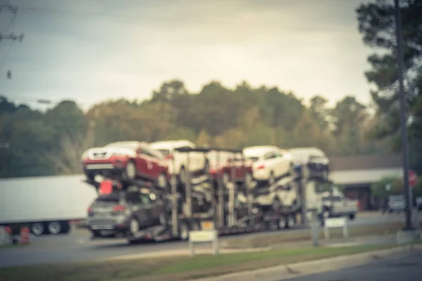 Vintage tone blurred huge car carrier truck of new cars for batch delivery to dealership. Full load transport truck of new vehicles in transit  in Texas, USA. Automotive industry abstract background