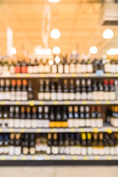 Blurred image of wine shelves with price tags on display at store in Houston, Texas, US. Defocused rows of Wine Liquor bottles on the supermarket shelf. Alcoholic beverage abstract background.