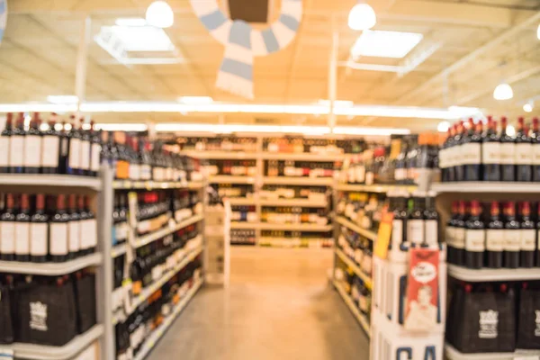 Blurred image of wine shelves with price tags on display at store in Houston, Texas, US. Defocused rows of Wine Liquor bottles on the supermarket shelf. Alcoholic beverage abstract background.