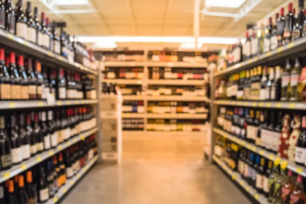 Blurred image of wine shelves with price tags on display at store in Houston, Texas, US. Defocused rows of Wine Liquor bottles on the supermarket shelf. Alcoholic beverage abstract background.