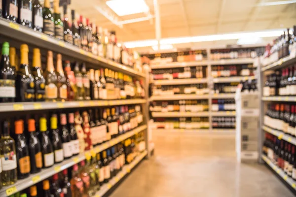 Blurred image of wine shelves with price tags on display at store in Houston, Texas, US. Defocused rows of Wine Liquor bottles on the supermarket shelf. Alcoholic beverage abstract background.