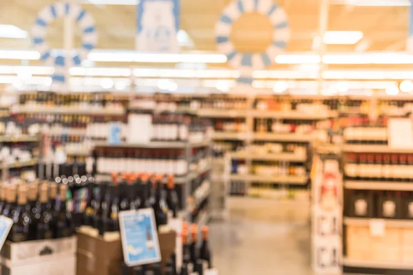 Blurred image of wine shelves with price tags on display at store in Houston, Texas, US. Defocused rows of Wine Liquor bottles on the supermarket shelf. Alcoholic beverage abstract background.