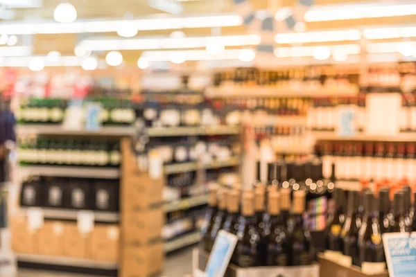 Blurred image of wine shelves with price tags on display at store in Houston, Texas, US. Defocused rows of Wine Liquor bottles on the supermarket shelf. Alcoholic beverage abstract background.