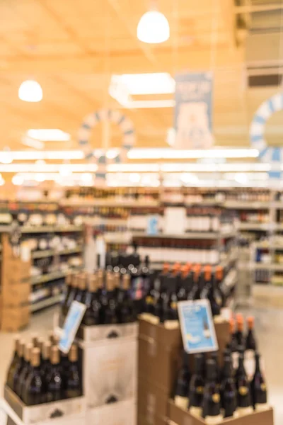 Blurred image of wine shelves with price tags on display at store in Houston, Texas, US. Defocused rows of Wine Liquor bottles on the supermarket shelf. Alcoholic beverage abstract background.