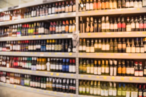 Blurred image of wine shelves with price tags on display at store in Houston, Texas, US. Defocused rows of Wine Liquor bottles on the supermarket shelf. Alcoholic beverage abstract background.