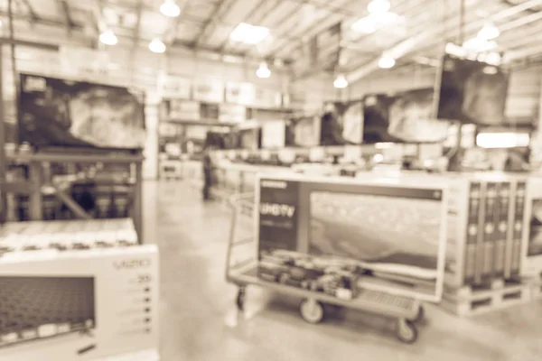 Vintage tone blurred TVs shopping at large wholesale club. Television retail shop, row of big screen, smart TVs. Customers browsing to select and use flatbed cart to carry TV to checkout counter