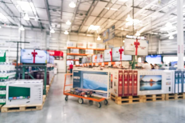 Vintage tone blurred TVs shopping at large wholesale club. Television retail shop, row of big screen, smart TVs. Customers browsing to select and use flatbed cart to carry TV to checkout counter