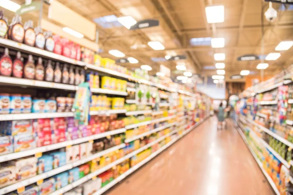 Motion blurred customer shopping for natural coffee, tea, water, bottled tea, energy drinks aisle in store at Houston, Texas, US. Wide view supermarket shelves, variety of products display bokeh light