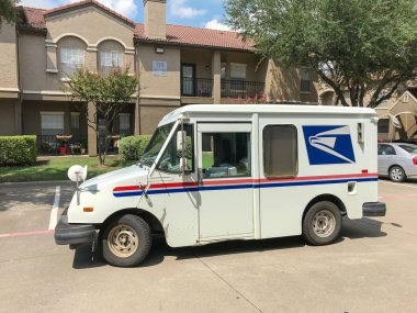 White USPS truck stops at apartment building complex on sunny da clipart