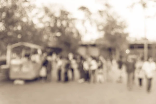 Vintage tone blurred long people queuing in front of an ice-cream wagon vendor at city park in Houston, Texas, US. Defocused local people and tourist waiting to buy cold drink, fresh juice. Side view