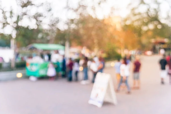 Vintage tone blurred long people queuing in front of an ice-cream wagon vendor at city park in Houston, Texas, US. Defocused local people and tourist waiting to buy cold drink, fresh juice. Side view