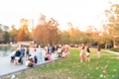 Bulanık görüntü çocuklar çim çim ve oturma ve Houston, Texas, gölde doğru merdivenlerde temiz hava zevk insanlar üzerinde çalışan bize. Ufuk açık Aile aktiviteleri lake city Park yakınındaki gün batımında