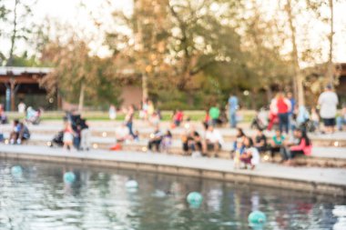 Bulanık oturan ve Houston, Texas, gölde doğru merdivenlerde temiz hava zevk görüntü insanlar bize. Ufuk arka plan açık hava etkinlikleri kalabalık insan Şehir Parkı gölde gün batımında yakınındaki..