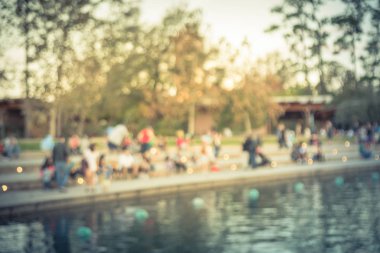 Bulanık oturan ve Houston, Texas, gölde doğru merdivenlerde temiz hava zevk görüntü insanlar bize. Ufuk arka plan açık hava etkinlikleri kalabalık insan Şehir Parkı gölde gün batımında yakınındaki..