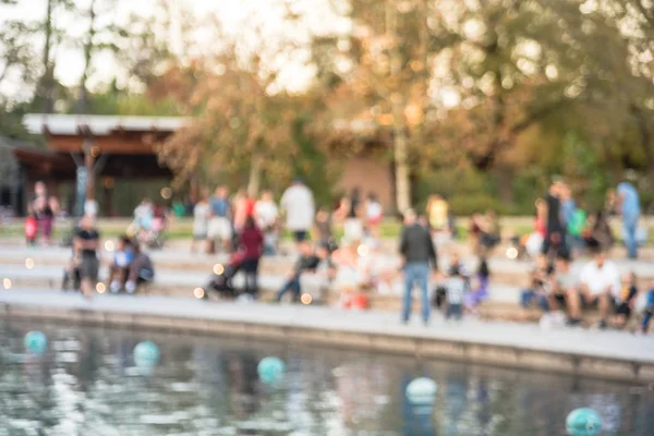 Bulanık oturan ve Houston, Texas, gölde doğru merdivenlerde temiz hava zevk görüntü insanlar bize. Ufuk arka plan açık hava etkinlikleri kalabalık insan Şehir Parkı gölde gün batımında yakınındaki..