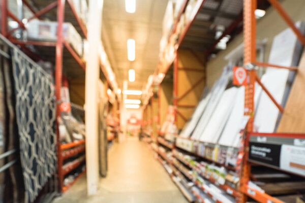 Blurred a large hardware store. Defocused interior of home improvement retailer with aisles, shelves and racks of merchandise tool for house repair from floor to ceiling. Inventory, wholesale concept