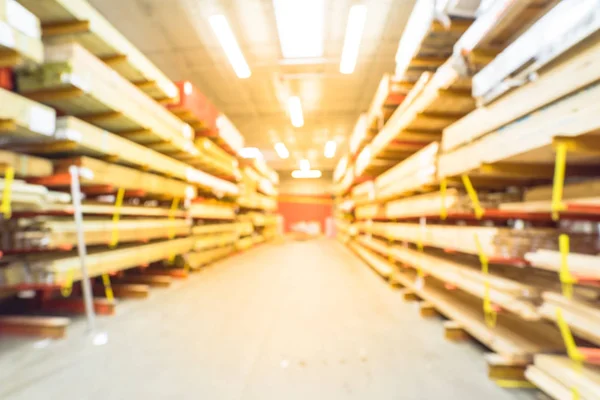 Blurred stack of new wooden bars on shelves inside lumber yard of large hardware store in America. Rack of fresh mill/cut wood timber in warehouse. Industrial wood texture and construction background.