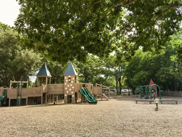 フォートや異なる年齢のための別のセクションと城のような公共の木製子供遊び場 テキサス アメリカ 夏の緑葉 空青い雲で大きな木の緑豊かな下セット構造を再生します — ストック写真
