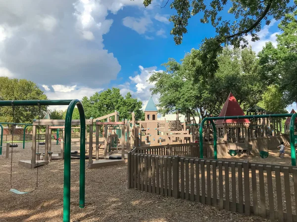 アーチ スイング コッペル テキサス 米国で大きな木の緑豊かな下公共の木子供の遊び場を設置します 夏葉の緑に囲まれたセットの構造を再生し 青い空の雲 — ストック写真