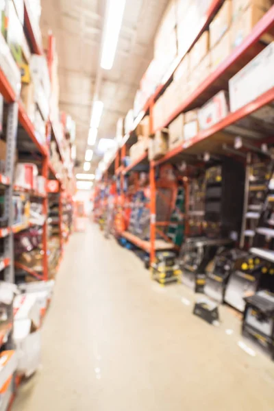 Blurred large hardware store in America. Defocused interior home improvement retailer with racks of signs, mailboxes, wet/dry vacuums, attic stairs, ladders and building materials floor up to ceiling