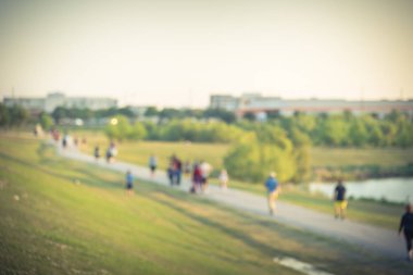 Vintage sesi bulanık grup enerjik insanlar koşu, yürüyüş, Çalıştır, itme bebek arabası ve bisiklet yolu yeşil ağaçlı, Houston, Teksas, çim şehir parkında aracılığıyla bize. Gün batımında soyut hareket açık egzersiz