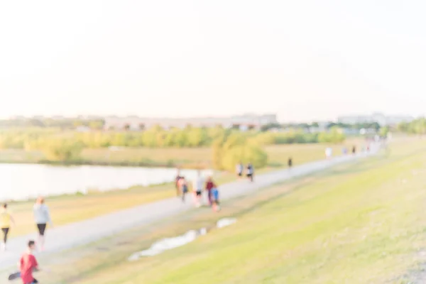 Blurred group of energetic people jog, walk, run, push stroller and bike through pathway with green tree, grass in city park at Houston, Texas, US. Abstract motion outdoor exercise. Healthy lifestyle