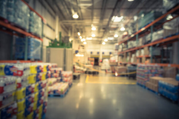 Vintage tone blurred large warehouse with worker stack goods with forklift, pallet, flatbed cart. Defocused industrial distribution aisles, shelves from floor to ceiling. Inventory, wholesale concept