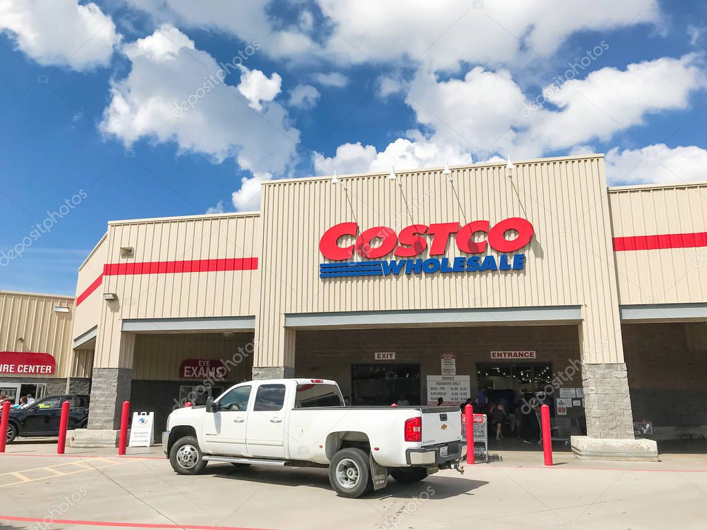 Lewisville, TX, USA-SEPT 15, 2018:White truck driving by entrance facade of Costco Wholesale storefront. It is the largest membership-only warehouse club in USA, sunny summer cloud blue sky