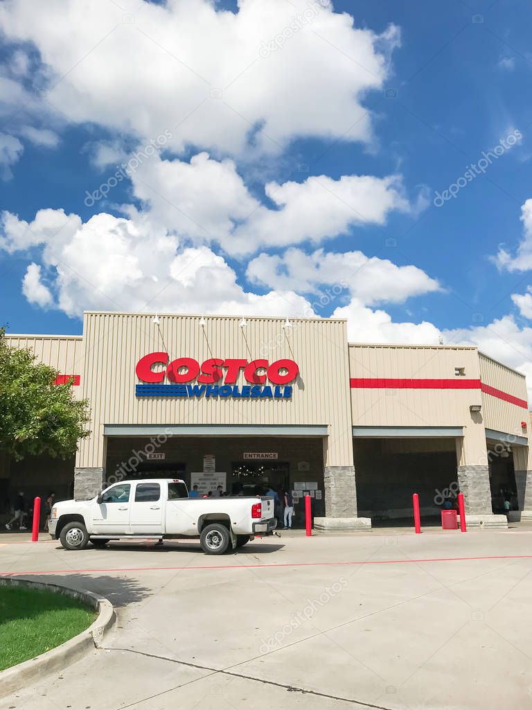 Lewisville, TX, USA-SEPT 15, 2018:White truck driving by entrance facade of Costco Wholesale storefront. It is the largest membership-only warehouse club in USA, sunny summer cloud blue sky