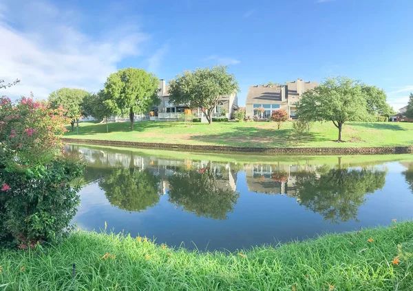 Panorama view mirror reflection of typical riverside houses surrounded by mature trees in Irving, Texas, USA.