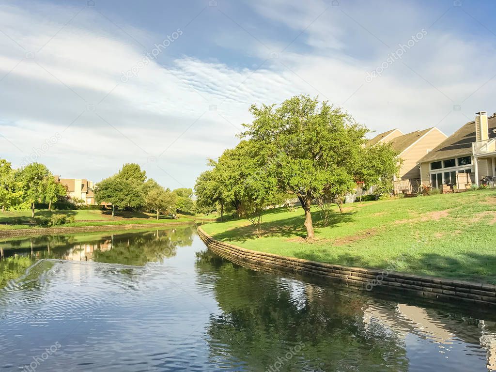 Mirror reflection of typical riverside houses surrounded by mature trees in Irving, Texas, USA.