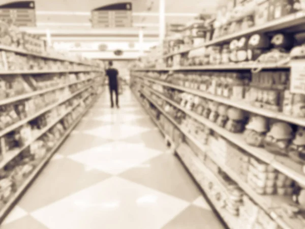 Vintage tone blurred abstract customer shopping for cookies, candies, snacks, preserved fruits at Asian grocery store in US. Defocused snack time treats aisle on display with price tags at supermarket