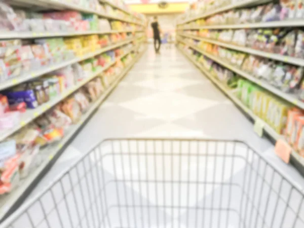 Motion blurred aisle of cookies, candies, snacks, preserved fruits with shopping cart at Asian grocery store in America. Defocused snack time treats aisle on display with price tags at supermarket