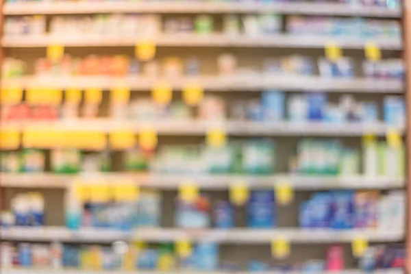 Blurred abstract background inside pharmacy store with arranged variation of pharmaceutical and medical supplies product in label on shelves display. Indoor drug store with blurred medicines. Panorama