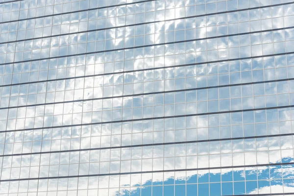 Close-up detail shot of cloud reflection on glass wall of modern business building in America. Steel light blue background of high-rise commercial skyscraper, the city of future concept