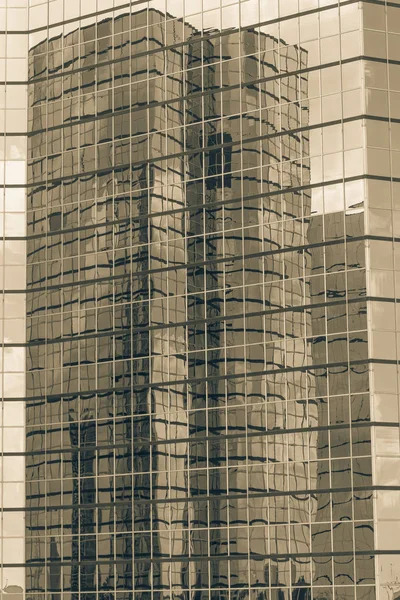 Vintage tone clouds and mirror building reflected in windows of modern office workspace. Steel light blue background of glass high-rise commercial skyscraper, the city of future concept