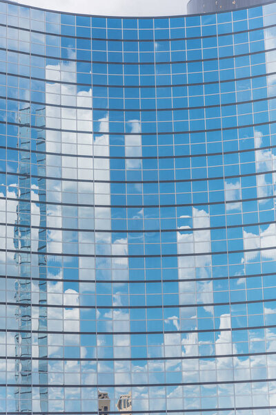 Close-up detail shot of cloud reflection on glass wall of modern business building in America. Steel light blue background of high-rise commercial skyscraper, the city of future concept