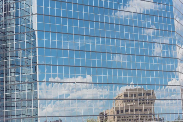 Clouds and mirror building reflected in windows of modern office workspace. Steel light blue background of glass high-rise commercial skyscraper, the city of future concept