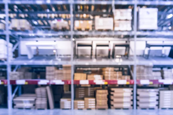 Blurred full-frame image aisles and bins at furniture warehouse in America. Defocused abstract industrial storehouse interior full of boxes, shelves, racks from floor to ceiling