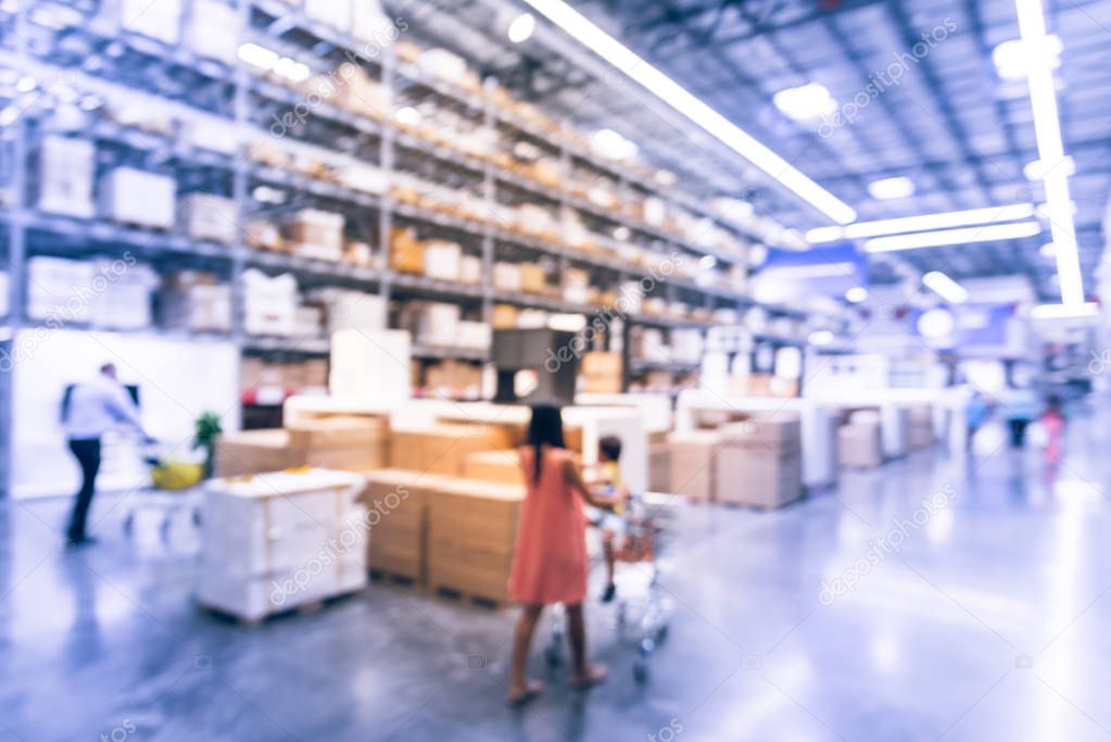 Abstract blurred customer shopping at large furniture warehouse in Texas, America. Defocused interior industrial storehouse full of boxes, row of aisles, bins, shelves, racks from floor to ceiling