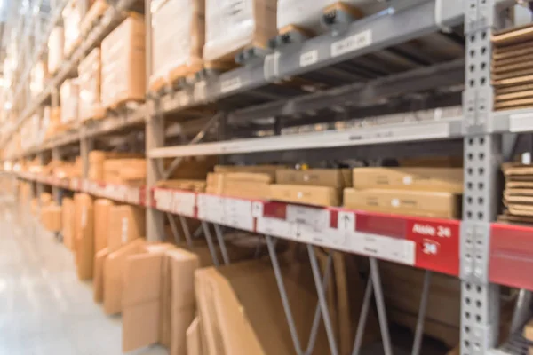 Abstract blurred large furniture warehouse with row of aisles and bins from floor to ceiling. Defocused background industrial storehouse inventory interior rack of big boxes home accessories