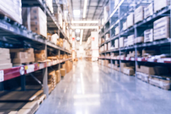 Abstract blurred large furniture warehouse with row of aisles and bins from floor to ceiling. Defocused background industrial storehouse inventory interior rack of big boxes home accessories