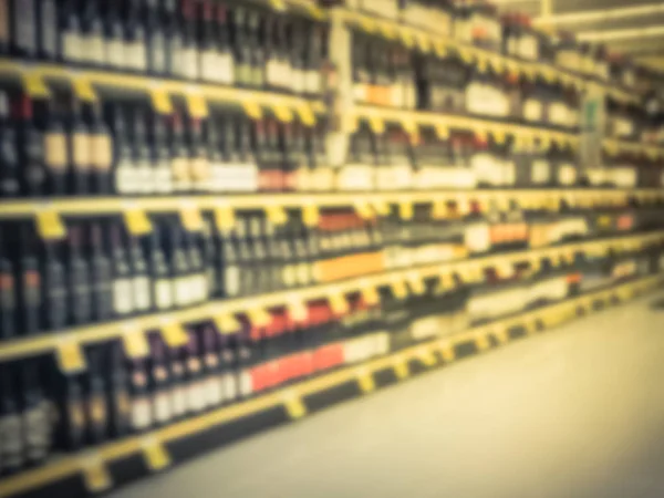 Blurred abstract wine aisle with price tags at grocery store in Texas, America. Defocused rows of red, white wine liquor bottles on supermarket shelf. Alcoholic beverage concept background
