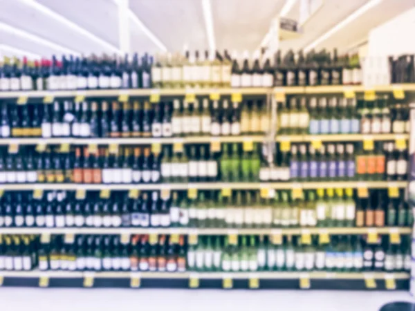 Blurred abstract wine aisle with price tags at grocery store in Texas, America. Defocused rows of red, white wine liquor bottles on supermarket shelf. Alcoholic beverage concept background