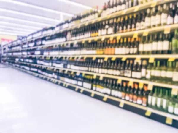 Blurred abstract wine aisle with price tags at grocery store in Texas, America. Defocused rows of red, white wine liquor bottles on supermarket shelf. Alcoholic beverage concept background