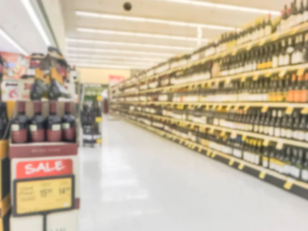 Blurred abstract wine aisle with price tags at grocery store in Texas, America. Defocused rows of red, white wine liquor bottles on supermarket shelf. Alcoholic beverage concept background