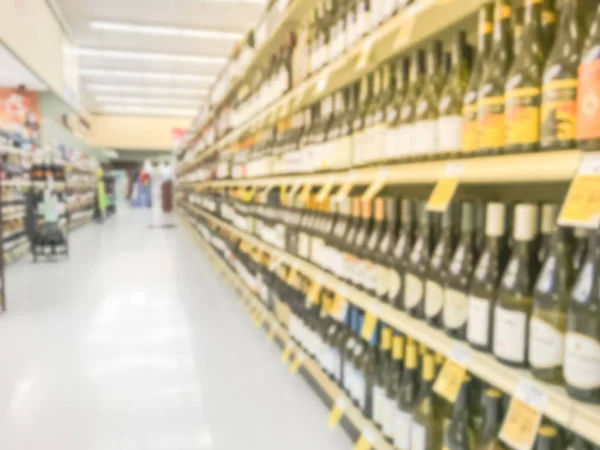 Blurred abstract wine aisle with price tags at grocery store in Texas, America. Defocused rows of red, white wine liquor bottles on supermarket shelf. Alcoholic beverage concept background