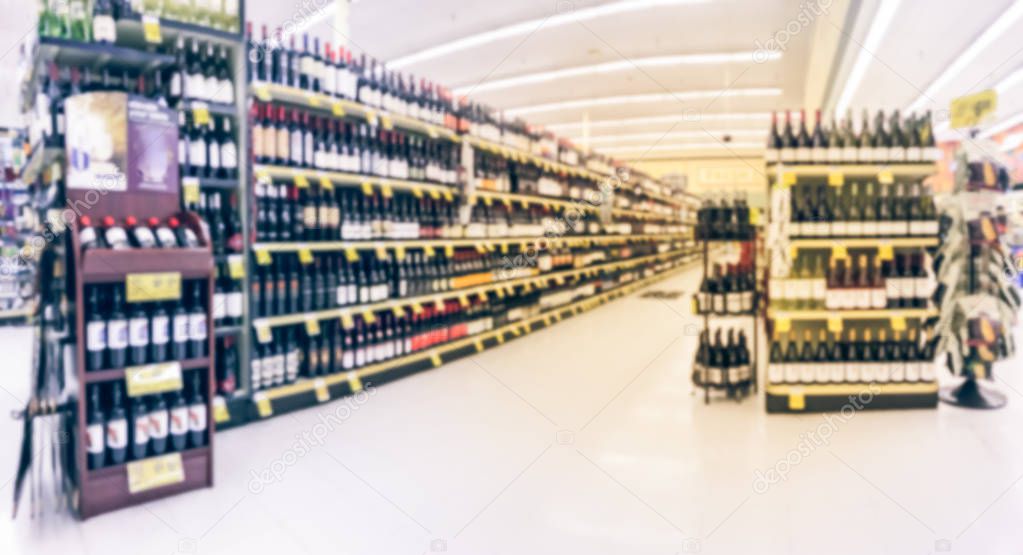 Panorama view blurred wine aisle with price tags at grocery store in Texas, America. Defocused rows of red, white wine liquor bottles on supermarket shelf. Alcoholic beverage abstract background