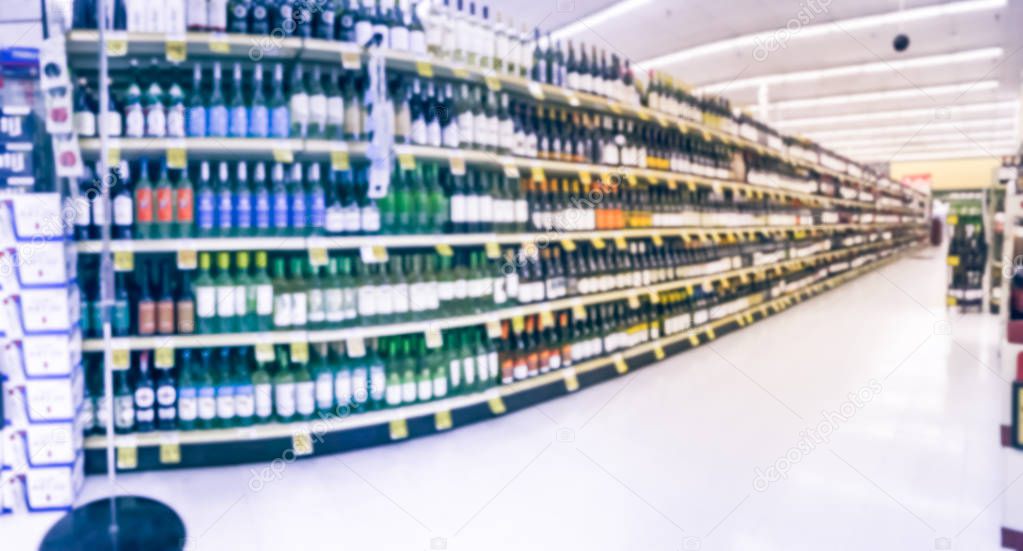 Panorama view blurred wine aisle with price tags at grocery store in Texas, America. Defocused rows of red, white wine liquor bottles on supermarket shelf. Alcoholic beverage abstract background